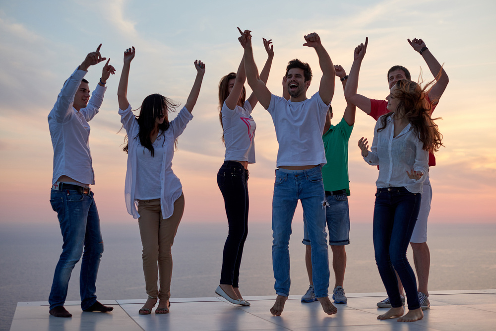 Group of adults with their arms up celebrating. 